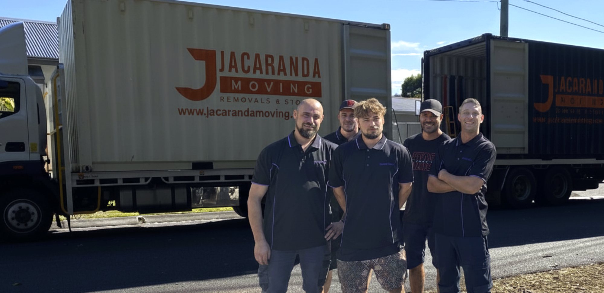 Jacaranda Moving crew standing in front of branded removal trucks